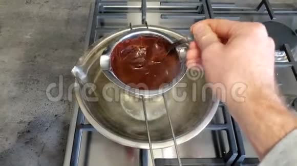 将融化的巧克力搅拌在一个小豆子中以阻止手工巧克力糖果生意浇注视频的预览图