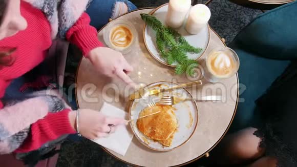 两个年轻的女人坐在咖啡馆里吃煎饼切煎饼上景视频的预览图