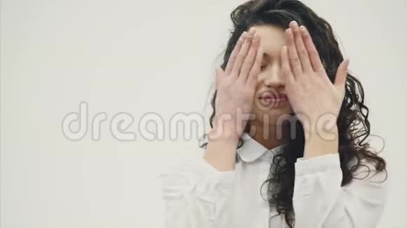 一位年轻漂亮的黑发商务女性的特写肖像双手闭上你的脸张开视频的预览图