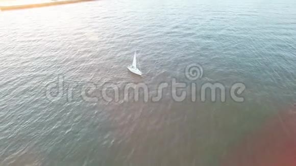 在灿烂的日落中在阳光明媚的耀斑和光线下从海岸航行的游艇的空中视野视频的预览图