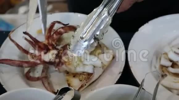 手用剪刀把烤鱿鱼切成小块然后放在白色的盘子里视频的预览图