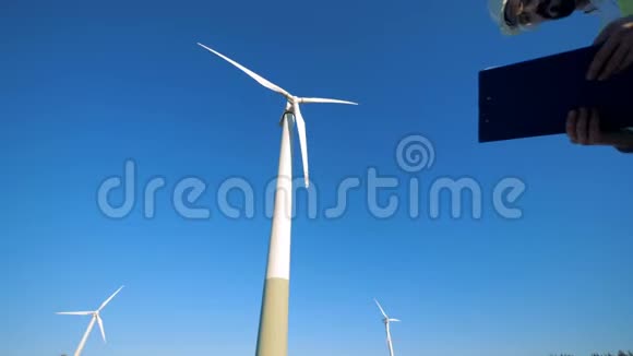 工人站在风力涡轮机附近在剪贴板上读纸可再生电能绿色能源概念视频的预览图