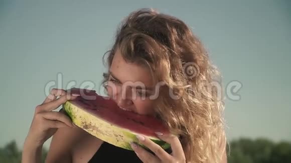 可爱的女人挥舞着头发在户外吃西瓜的肖像年轻的女孩享受她的休息和微笑视频的预览图