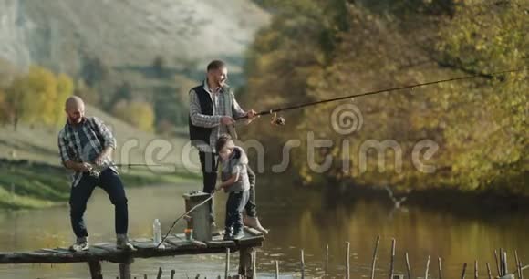 两个男人和一个小男孩用两根鱼竿从湖里钓鱼视频的预览图