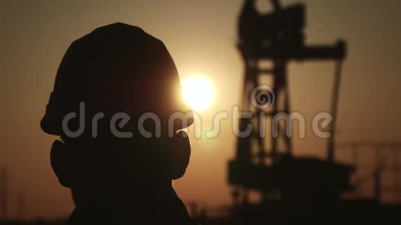 夕阳西下石油化工石油钻机泵工程师剪影工人站在的背景上视频的预览图