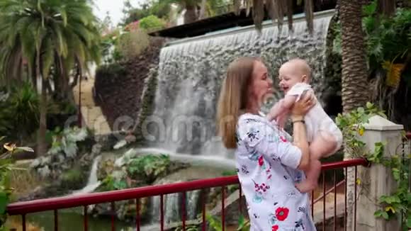 宝贝和妈妈在瀑布附近玩快乐的家人出去散步视频的预览图