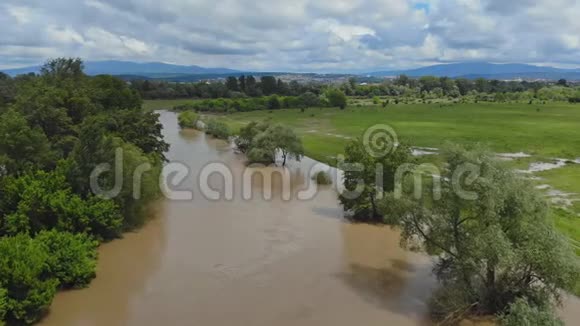 乡村沿着河流的高水位洪水泛滥的草地多云的天空视频的预览图