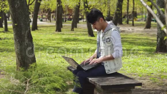 在公园里用黑色笔记本电脑工作的自由职业者视频的预览图