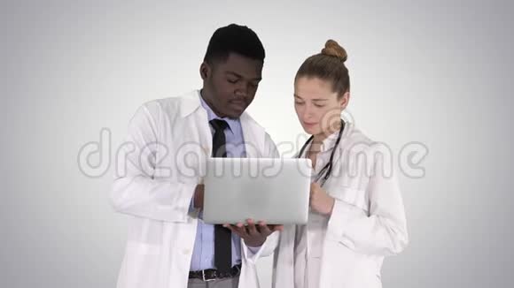 医务人员在灰色笔记本电脑前工作同时站在梯度背景上视频的预览图