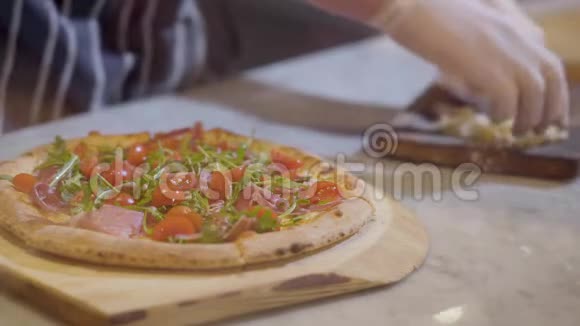 厨师把配料放在披萨上然后在木板上撒上奶酪烹饪披萨视频的预览图