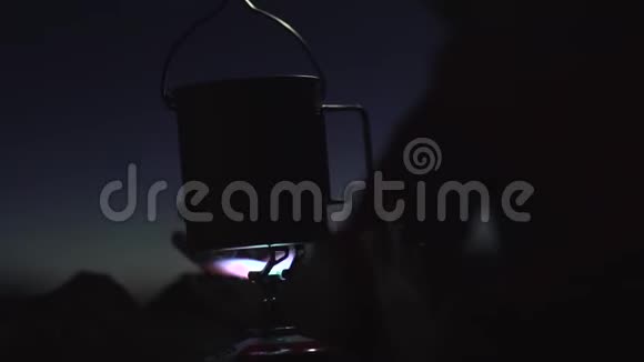 女孩打开一盏前照灯用煤气火炬的火焰温暖她的手在山里的夜晚视频的预览图