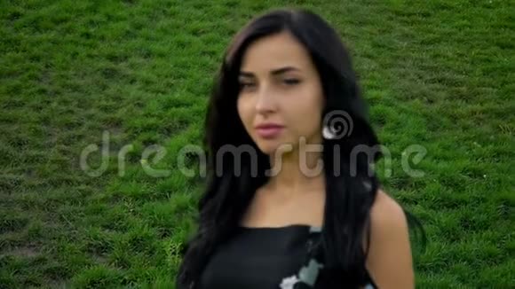 绿草背景下一个黑发女人的肖像视频的预览图