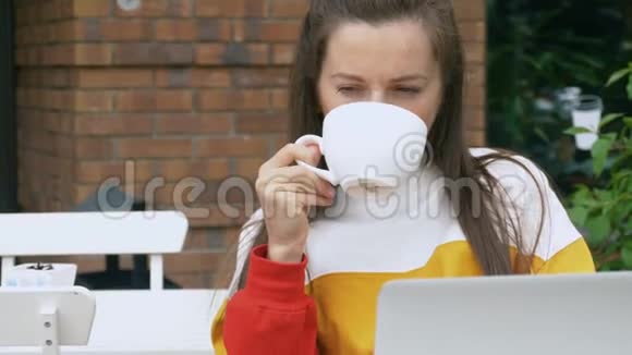 女人喝咖啡用笔记本电脑视频的预览图