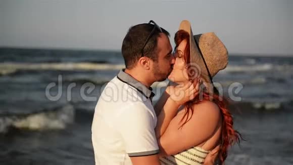 日落时分一对浪漫的情侣在海滩上亲吻和拥抱柔和的阳光色请看背景视频的预览图