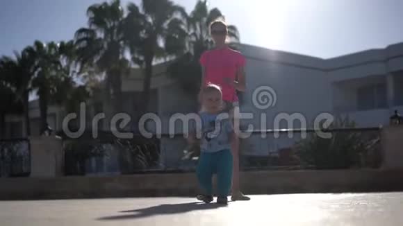 母亲带着孩子走在棕榈树附近的街道上视频的预览图