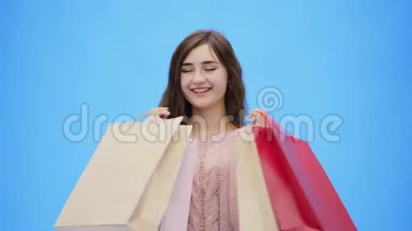 年轻漂亮的女孩在做令人难以置信的令人愉快的购物在此期间她举起双手和购物袋在同一时间视频的预览图
