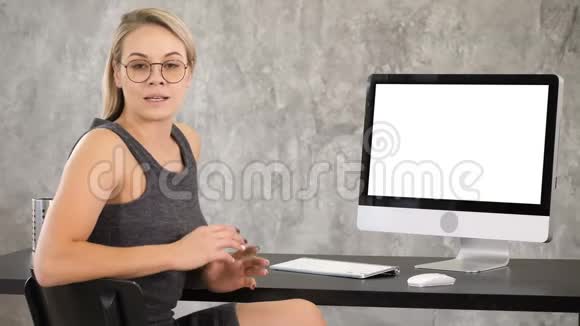 漂亮的年轻女人戴着眼镜对着镜头说话白色显示器视频的预览图