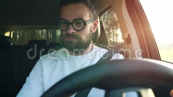 戴眼镜的人在日落时停在停车场的车里视频的预览图