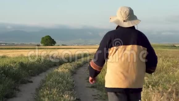 在夏天的下午跟着一个带着跋涉杆在农村散步的老徒步旅行者视频的预览图