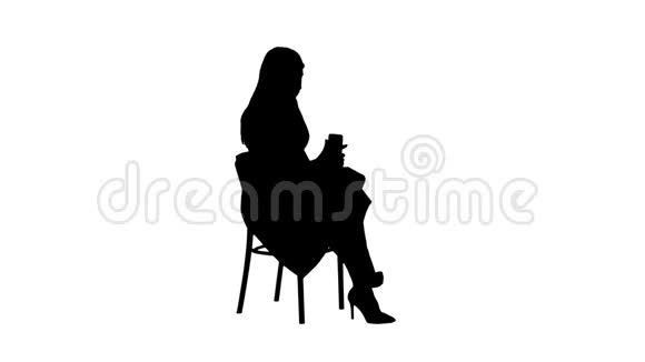 剪影年轻的女人金发坐在椅子上看书在手机上发短信视频的预览图