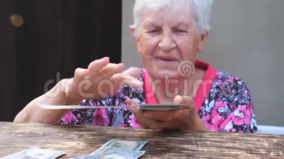 幸福的祖母手里拿着一捆钱把外币撒在桌子上的肖像老人微笑视频的预览图