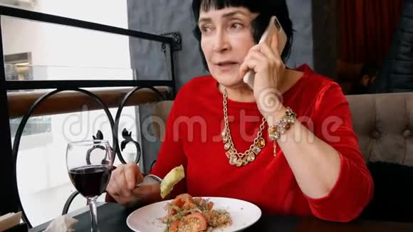 优雅的高级女人在餐馆或咖啡馆里吃沙拉喝葡萄酒视频的预览图