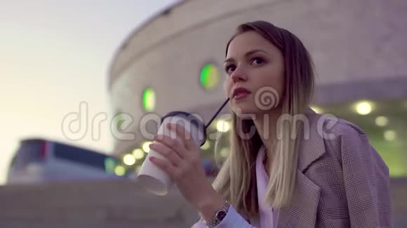 夜城中年轻迷人的女孩穿上夹克喝着咖啡看着电话视频的预览图