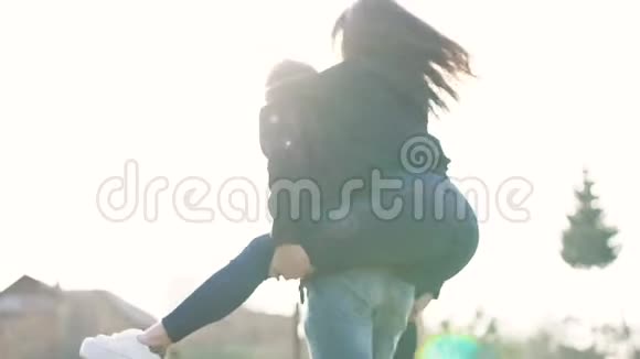 快乐的女孩跳在男人背上慢动作浪漫的散步视频的预览图