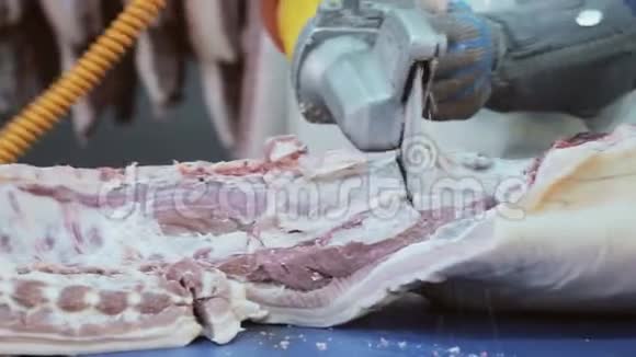一个工人用电锯切割猪肉猪肉的脱粘把肉切成碎片视频的预览图
