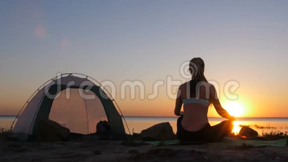 日落时分在海滩上摆着莲花的女人视频的预览图