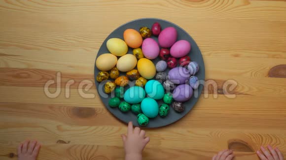 孩子们手拿盘子里的多色复活节彩蛋视频的预览图