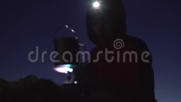女孩打开一盏前照灯用煤气火炬的火焰温暖她的手在山里的夜晚视频的预览图