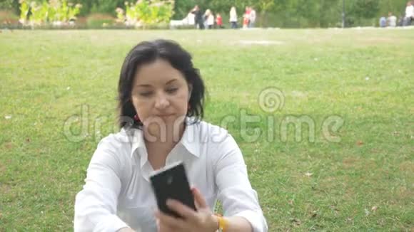 一个女人看着电话她躺在草坪上视频的预览图