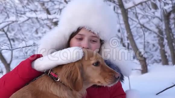 孩子们在森林里玩他的宠物美丽的女孩微笑着在冬天抚摸她心爱的狗视频的预览图