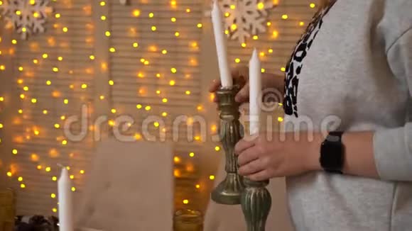 女人或女孩用手装饰圣诞或新年晚餐的桌子手把蜡烛放在节日的烛台上视频的预览图