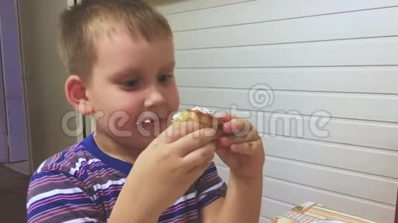 可爱的男孩在家吃美味的纸杯蛋糕里面有鲜奶油和水果视频的预览图