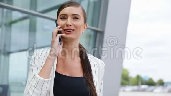 美丽的微笑的女人在商务办公室附近打电话视频的预览图