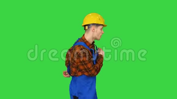 年轻的建筑工人在绿色屏幕上戴着安全帽的时髦舞蹈Chroma键视频的预览图