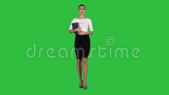 漂亮的年轻女人带着笔记本走在绿色屏幕上Chroma键视频的预览图
