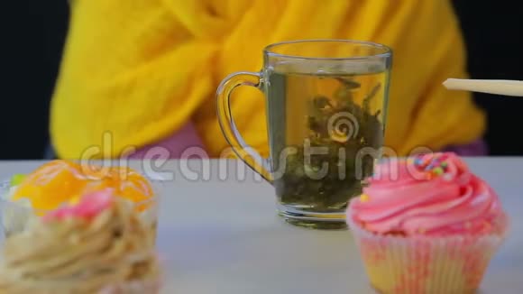 在灰色桌子上的透明杯子里用新鲜冲泡的绿茶和蛋糕视频的预览图