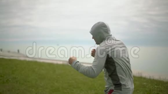 一个年轻的运动员在城市和湖泊的背景下训练拳击练习慢动作旋转摄像机视频的预览图