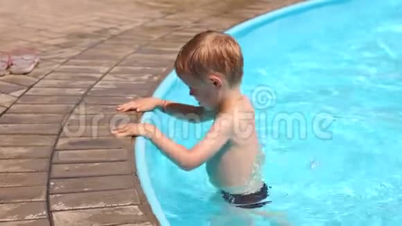 一个小男孩在暑假孩子们的游泳池里玩耍和跳跃视频的预览图