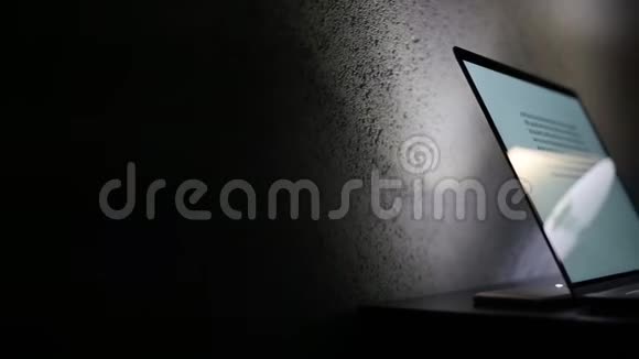 男性手在笔记本电脑键盘上打字的特写在黑暗的房间里视频的预览图