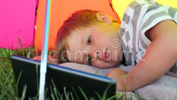 孩子拿着石碑躺在阳光伞下的绿草上暑假概念视频的预览图