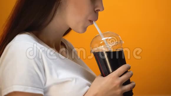 喝汽水微笑糖瘾高热量饮料的年轻妇女视频的预览图
