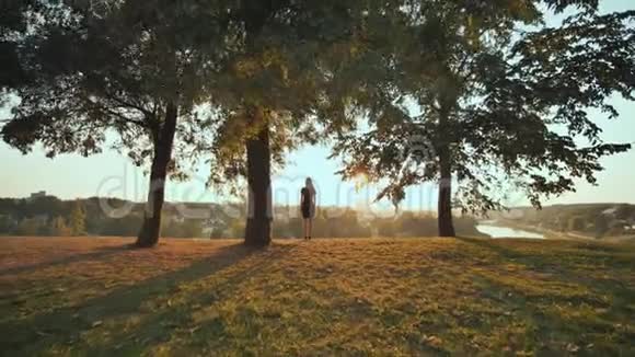 女孩热情地跑去迎接城市背景上的日落举起双手录像正在播放视频的预览图