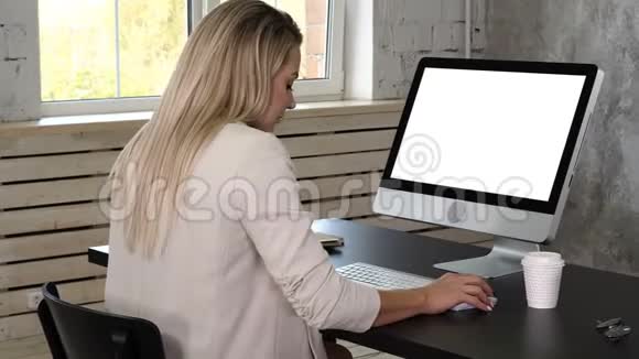 商务女性穿着衣服坐在靠近窗户的工作场所在办公室里使用电脑白色显示器视频的预览图