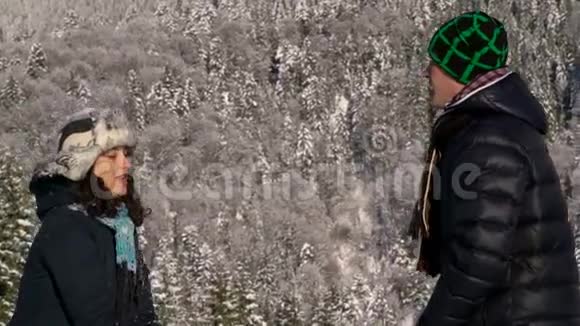 一对幸福的恋人走过白雪覆盖的森林他们扔雪和笑他和那个女孩视频的预览图