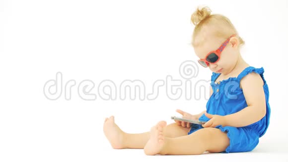 戴墨镜的女婴在智能手机上观看电影或卡通片视频的预览图