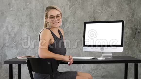 漂亮的女商人看着电脑屏幕附近的照相机白色显示器视频的预览图